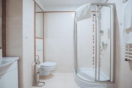 a white bathroom with a shower and a toilet at Miejsca noclegowe i Restauracja Kamiński in Kępno