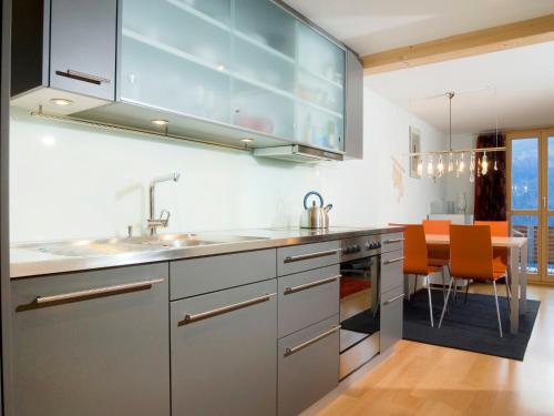 a kitchen with stainless steel appliances and orange chairs at Apartment Breithorn-Residence-2 by Interhome in Wengen