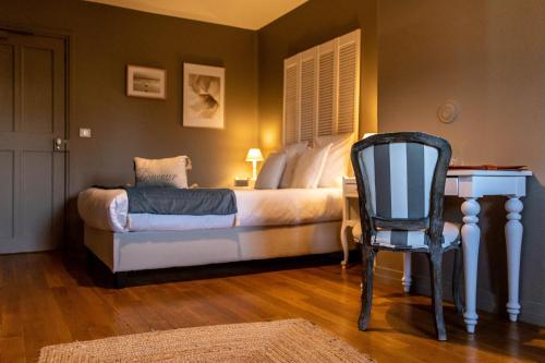a bedroom with a bed with a desk and a chair at Hotel Ô Château in Hayange