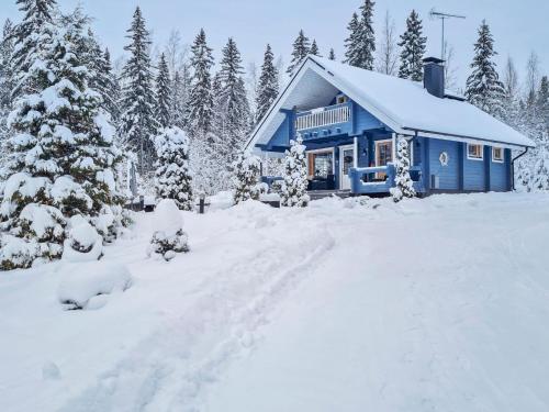 a blue house in the snow with snow covered trees at Holiday Home Willa klaara by Interhome in Patajoki