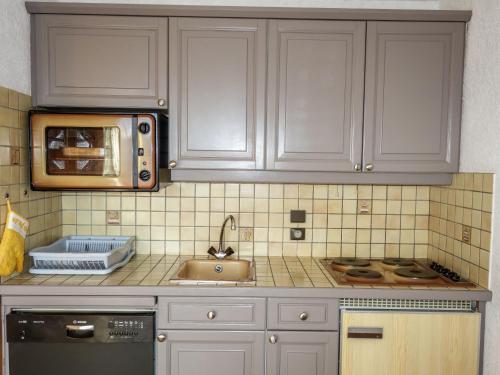 une cuisine avec des armoires blanches, un évier et un micro-ondes dans l'établissement Studio La pointe des Aravis 4 by Interhome, à Saint-Gervais-les-Bains