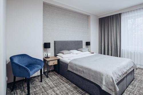 a hotel room with a bed and a blue chair at Miejsca noclegowe i Restauracja Kamiński in Kępno