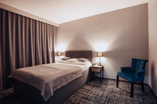 a hotel room with a bed and a blue chair at Miejsca noclegowe i Restauracja Kamiński in Kępno