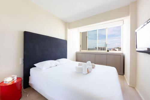 une chambre avec un lit blanc et une fenêtre dans l'établissement Appartement 70 m2 face à la mer, dernier étage, au bord des plages, à Cannes