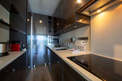 une cuisine avec des armoires noires et un comptoir dans l'établissement Appartement 70 m2 face à la mer, dernier étage, au bord des plages, à Cannes