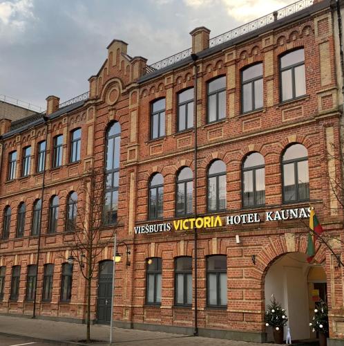 a large red brick building with a sign on it at VICTORIA Hotel Kaunas in Kaunas