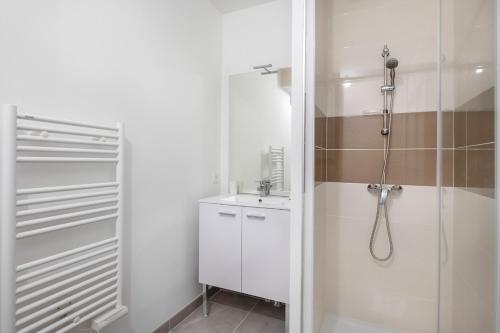 une salle de bain blanche avec une douche et un lavabo dans l'établissement À 210m de la plage, jolie maison pour 6, à Sarzeau
