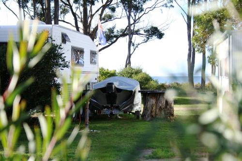a white camper with a tent in a yard at Captain Cook Holiday Park in Adventure Bay