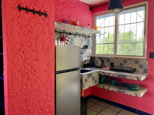 cocina con pared roja y refrigerador en YouCancun - cozy apartments in Cancún, en Cancún