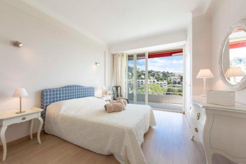 une chambre blanche avec un lit et une grande fenêtre dans l'établissement Appartement entièrement équipé de 105 m2 avec vue mer et collines, à Cannes