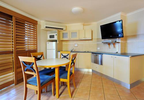 a kitchen with a table and chairs and a tv at at Boathaven Bay Holiday Apartments in Airlie Beach