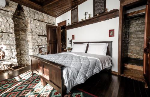 a bedroom with a bed and a stone wall at Hani i Xheblatit in Berat
