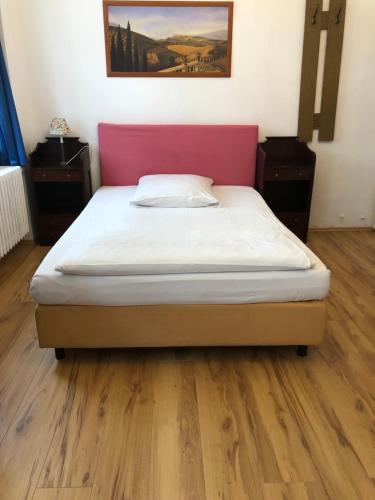 a bedroom with a bed with a pink head board at Hotel Galleria in Munich