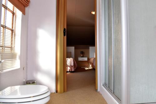 a bathroom with a toilet and a room with a bed at Villa Moria Peace Cottage in Dullstroom