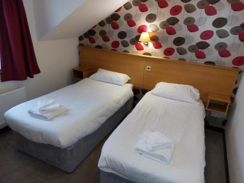 two beds in a hotel room with white sheets at The County Lodge in Carnforth