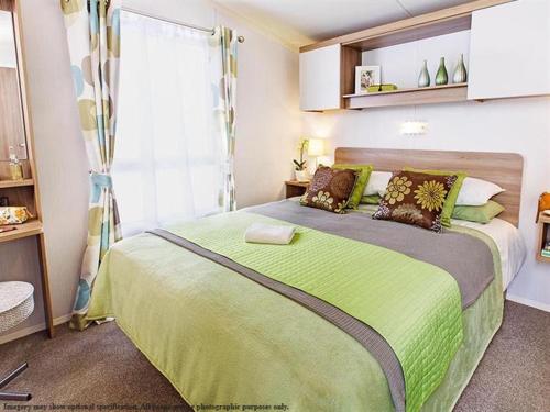 a bedroom with a large bed with a green blanket at Heavenly Haven in Lymington