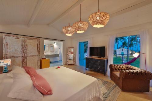 a bedroom with a bed and a television and chandeliers at Pousada Patacho in Pôrto de Pedras