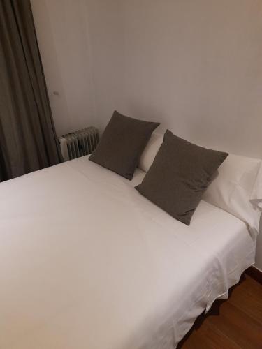 Una cama blanca con dos almohadas encima. en BV Rooms, en Madrid