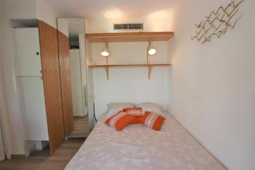 Cette petite chambre comprend un lit avec un oreiller orange. dans l'établissement Appartement climatisé bord de mer Palm beach avec grande terrasse, à Cannes