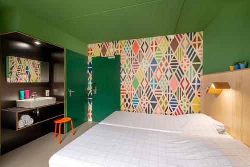 een slaapkamer met een wit bed en een kleurrijke muur bij Stayokay Hostel Dordrecht - Nationaal Park De Biesbosch in Dordrecht
