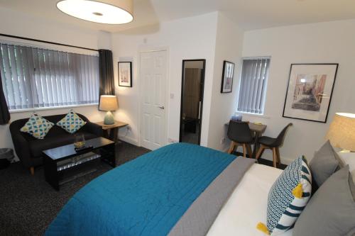 a bedroom with a blue bed and a couch at Anson Studios Walsall M6, J10 in Walsall