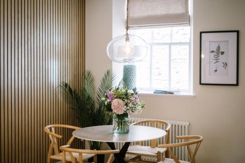 a vase of flowers on a table with chairs at The Den - The White House Windermere in Bowness-on-Windermere