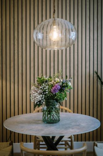 a vase of flowers on a table under a light fixture at The Den - The White House Windermere in Bowness-on-Windermere