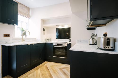 a kitchen with black cabinets and white counter tops at The Den - The White House Windermere in Bowness-on-Windermere