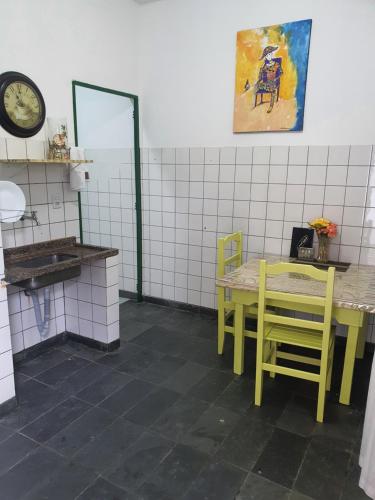 une cuisine avec une table, des chaises et une horloge dans l'établissement Suíte 06 Exclusiva e Independente, à Cuiabá