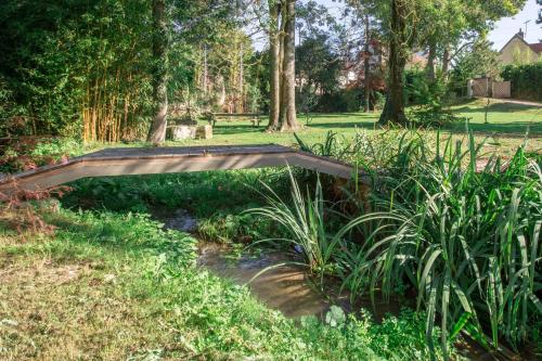 un puente de madera sobre un arroyo en un jardín en Villa Nature - Maya village, en Pougny