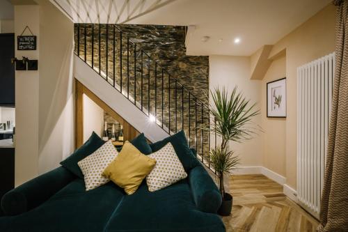 a living room with a blue couch and a staircase at The Den - The White House Windermere in Bowness-on-Windermere