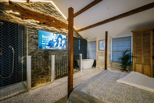 a bedroom with a tv on a brick wall at The Den - The White House Windermere in Bowness-on-Windermere