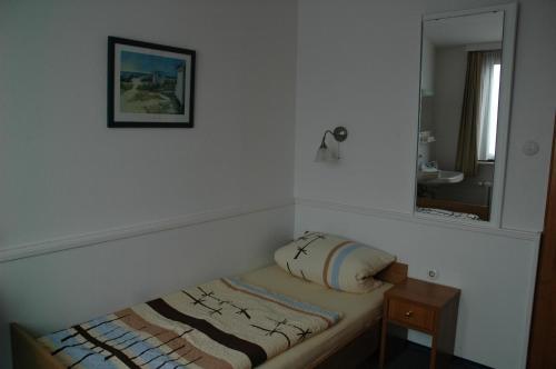 a small bed in a room with a mirror at Pension Haus Weierts in Norderney