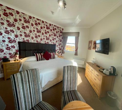a bedroom with a large bed with flowers on the wall at Langham Hotel Eastbourne in Eastbourne
