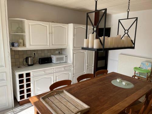 cocina con armarios blancos y mesa de madera en Maison 6 personnes avec piscine privée, en Saulchoy