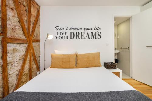 ein Schlafzimmer mit einem weißen Bett mit einem Schild, das liest, dass dein Leben nicht in Frage stellt in der Unterkunft WHome Martim Moniz Central Studio in Lissabon