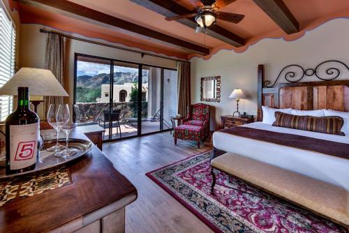 Hacienda del Sol Guest Ranch Resort في توسان: غرفة نوم مع سرير وطاولة مع زجاجة من النبيذ