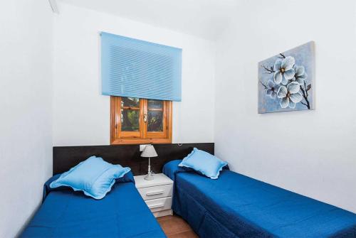 カラ・ブランカにあるTheaの青いシーツと窓が備わる客室で、ベッド2台が備わります。