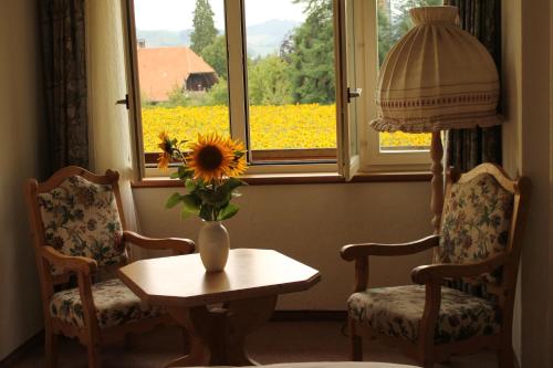a room with two chairs and a vase with a sunflower on a table at Gemeinschaftshaus im Oberdorf in Lützelflüh