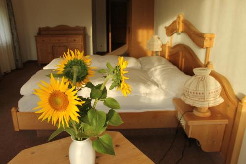 Gemeinschaftshaus im Oberdorf في Lützelflüh: سرير مع إناء من زهور الشمس على طاولة