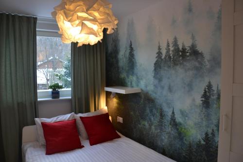 sypialnia z łóżkiem z czerwonymi poduszkami i obrazem w obiekcie Apartament przy Pijalni w mieście Krynica Zdrój