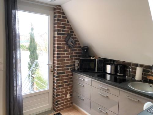 een keuken met een wastafel en een bakstenen muur bij Au Domaine Fresnois in Fresnes-lès-Montauban