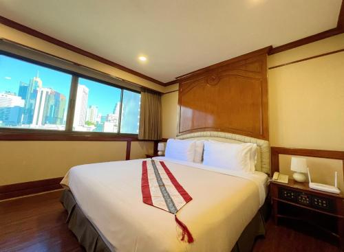 een hotelkamer met een groot bed en een raam bij The Promenade Hotel - SHA Plus in Bangkok
