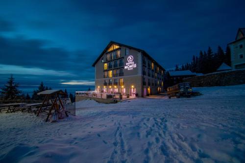 a building with a sign on it in the snow at Montis Hotel & Spa in Muntele Mic
