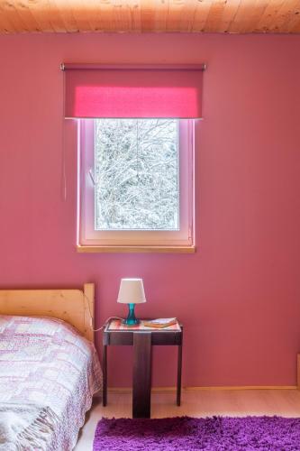 a bedroom with a red window and a table with a lamp at Villa Teodora in Kopaonik