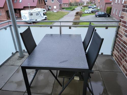een tafel en stoelen op een balkon met een trailer bij Ferienwohnung Krabbe im Haus-Neuharlingersiel in Neuharlingersiel