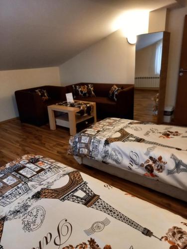 a bedroom with two beds and a couch and wooden floors at Guest rooms Bansko in Bansko