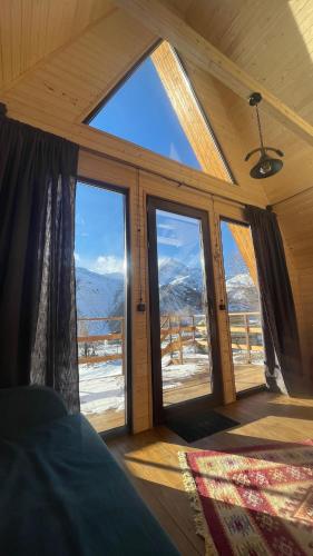 a bedroom with a view of the mountains through windows at AURA Cottages in Stepantsminda