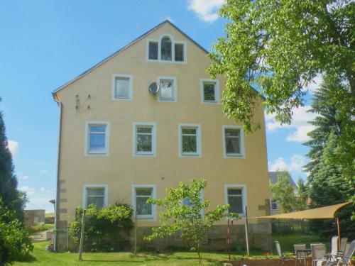 ein großes gelbes Haus mit weißen Fenstern und einem Baum in der Unterkunft Am Lindenbaum in Kirnitzschtal