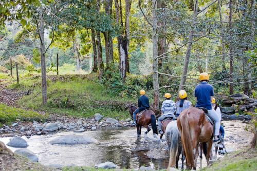a group of people riding horses through a stream at Savegre Hotel Natural Reserve & Spa in San Gerardo de Dota